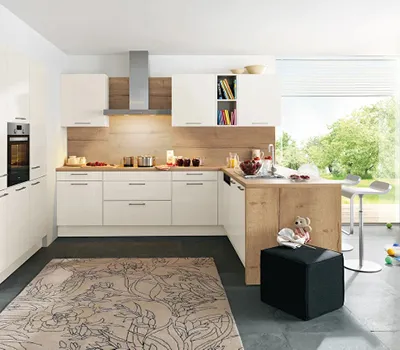 Helle L-Küche in Weiß mit Holzarbeitsplatte und gemütlicher Theke, ausgestattet mit modernen Elektrogeräten und viel Stauraum, ideal für familienfreundliches Kochen in modernem Design.